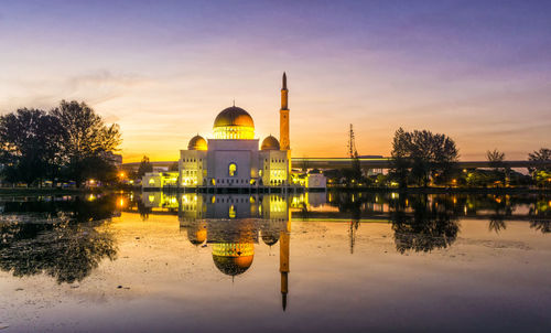 Reflection of illuminated church in lake against sky