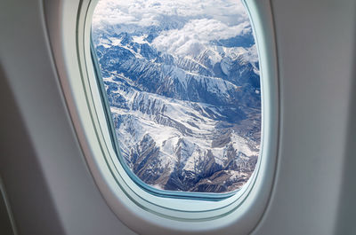 Aerial view of snowcapped mountains seen through airplane window