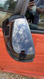 Reflection of man on side-view mirror of car