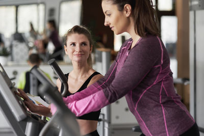 Instructor assisting woman in health club