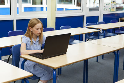 Young woman using mobile phone while sitting on table