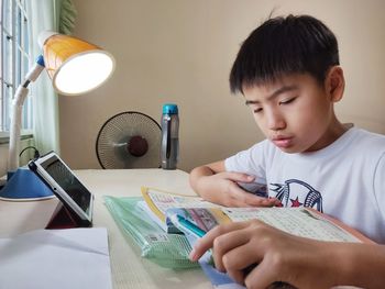 Portrait of a boy attending school online class with mobile device at home.