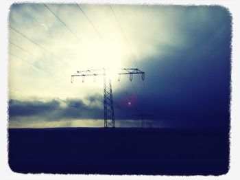 Low angle view of electricity pylon against cloudy sky