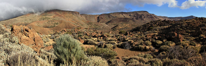 Panoramic view of rocky mountains against cloudy sky