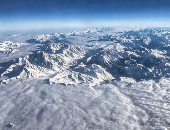 Aerial view of snowcapped mountains against blue sky