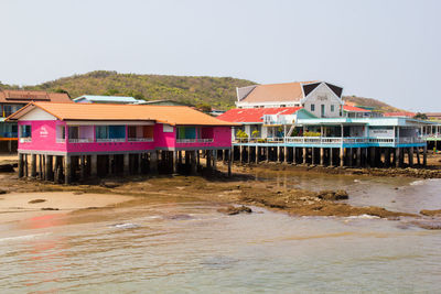 Houses by sea against clear sky