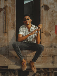 Portrait of young man sitting on old train trailer 