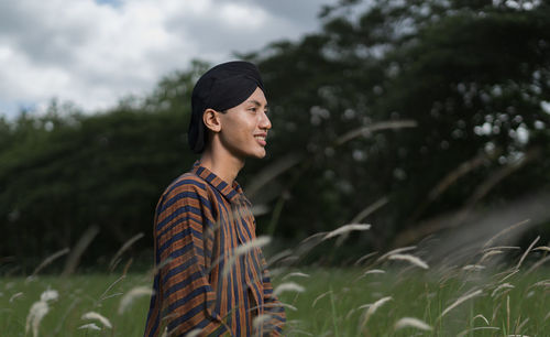 Smiling young man looking away on field