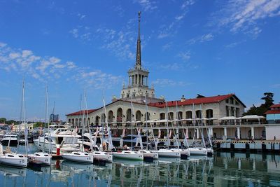 Sailboats moored at harbor against sky in city