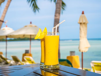 Yellow drink in glass on table against sea
