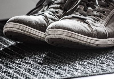 Low section of person wearing shoes on rug