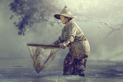 Side view of woman standing on rock by lake