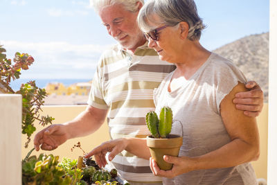 Man and woman by plants against sky