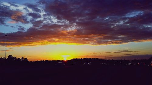 Silhouette landscape against dramatic sky during sunset