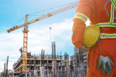 Low angle view of crane at construction site against sky