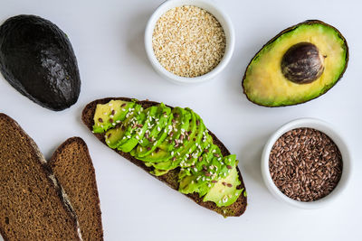 Ingredients for healthy avocado toast. ripe hass avocado, wholegrain bread, sesame flax seeds. vegan