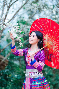 Young woman with red umbrella holding flowers