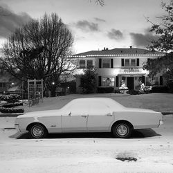 Car on street by buildings against sky