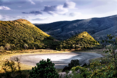 Scenic view of river by mountains against sky