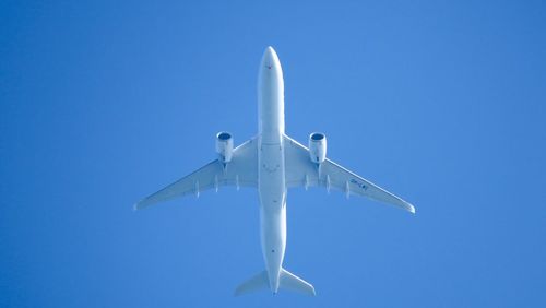 Low angle view of airplane flying against clear blue sky