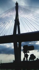 Low angle view of silhouette people on bridge against sky