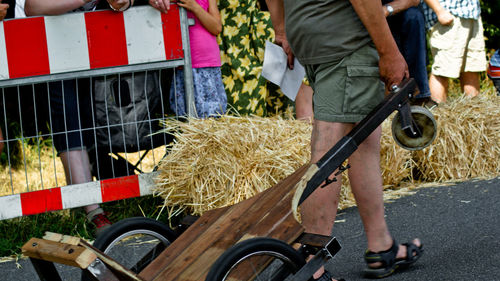 Low section of man with cart walking on road