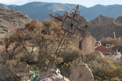 Metallic cross on tombstone against mountains