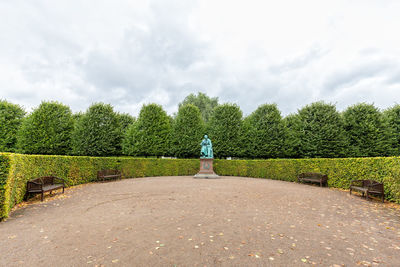 Statue and benches against hedge and trees at park