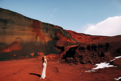 Woman standing against red rock mountains