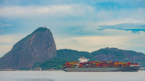 Photo of sugarloaf mountain with a cargo ship passing in front of it in guanabara bay