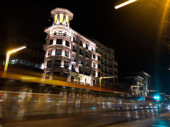 Light trails on street amidst buildings in city at night