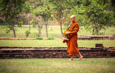Side view full length of monk walking on field