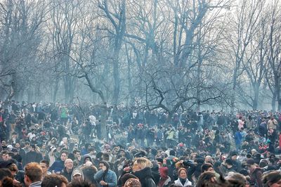 Crowd against bare trees during winter