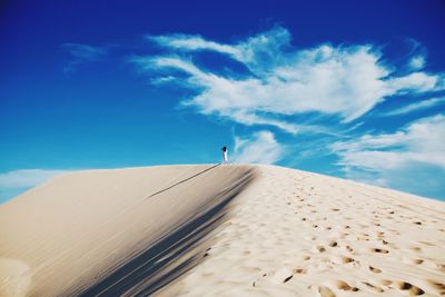 Man standing in desert against blue sky