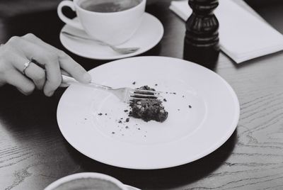 Cropped hand of woman cutting food in plate with fork