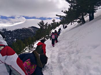 People on snowcapped mountain against sky