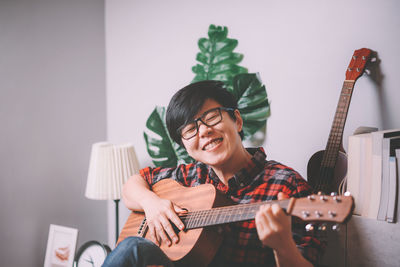 Portrait of man playing guitar at home