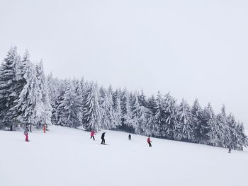 People on snow covered landscape against sky