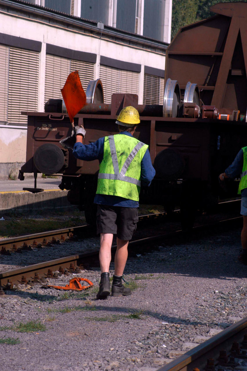 REAR VIEW OF MAN WORKING ON RAILROAD TRACKS