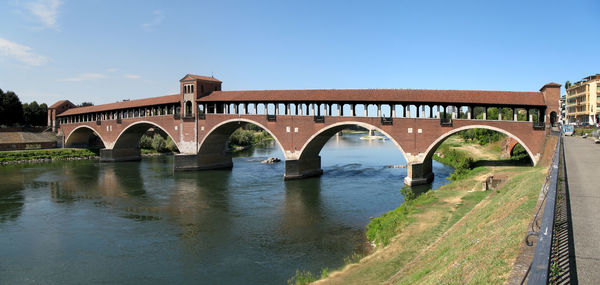 Arch bridge over river against blue sky