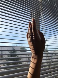 Cropped hand on window blinds