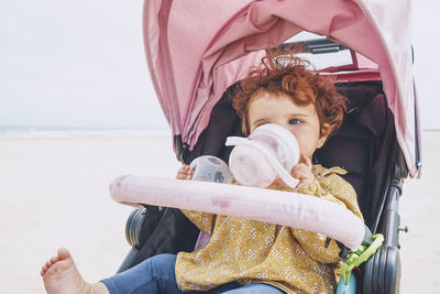 Cute girl drinking milk sitting on stroller