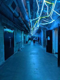 Illuminated footpath amidst buildings in city at night