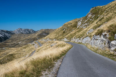 Road amidst mountains against clear blue sky