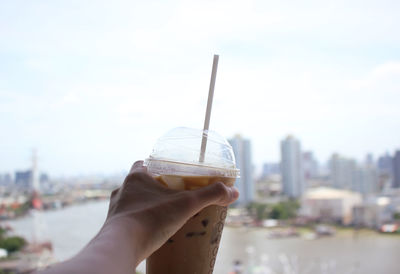 Close-up of hand holding ice cream against sky