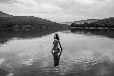 Man standing in lake against sky