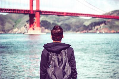 Rear view of man overlooking calm river