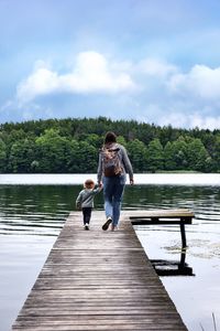 Portrait of woman sitting on pier over lake against sky