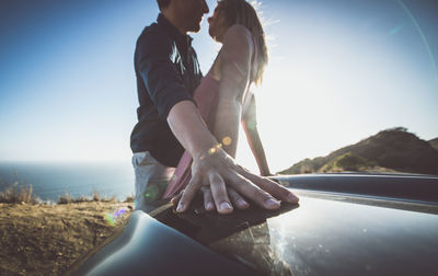 Couple kissing in water against sky