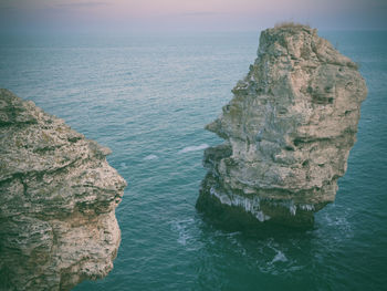 Rock formation in sea against sky